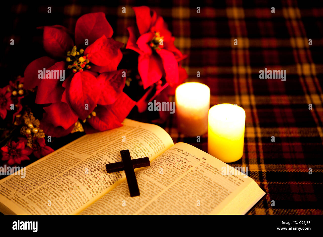 A crucifix on an open bible with illuminated candle and flowers Stock Photo