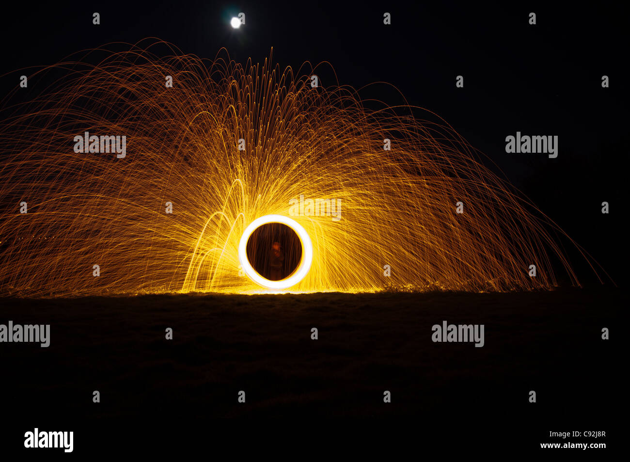 Steel wool spinning, creating gorgeous circular streaks of golden light from burning wire wool inside a whisk attached to wire, or rope. Stock Photo