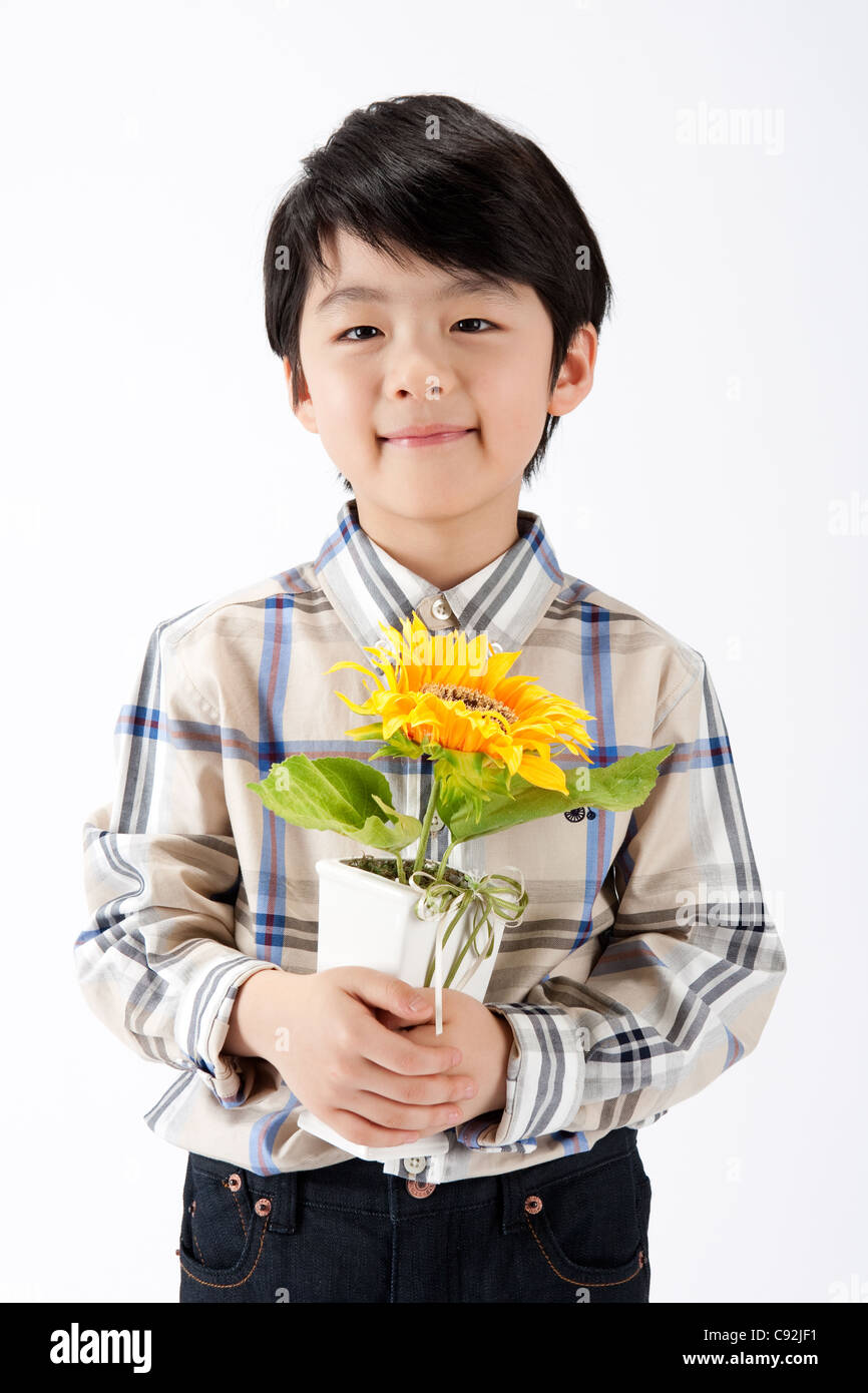 A boy holding potted flower plant, portrait Stock Photo - Alamy