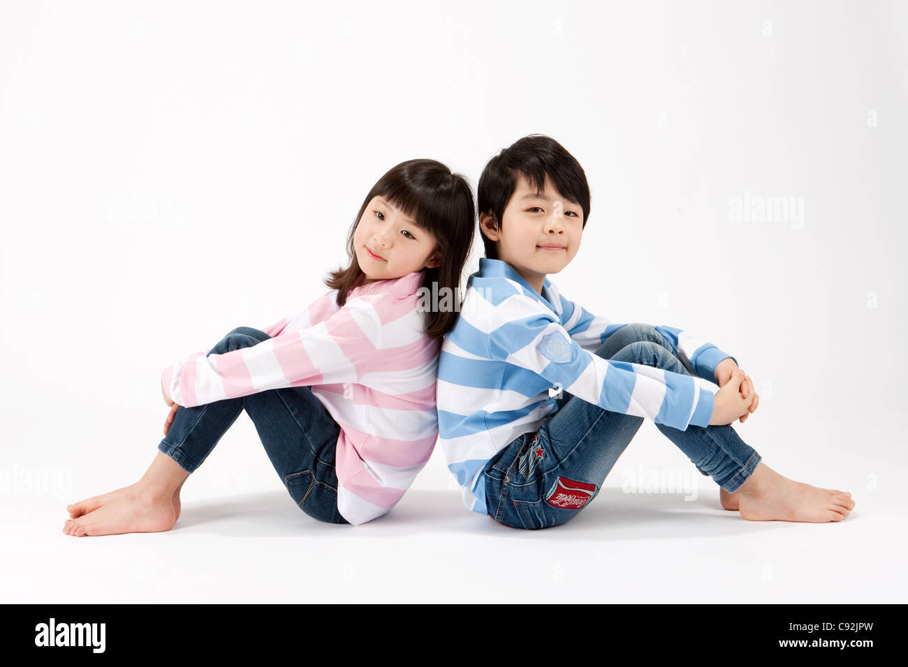 Boy and girl sitting back to back Stock Photo - Alamy