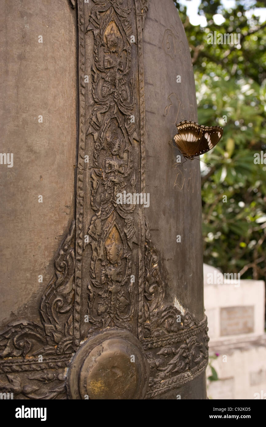 Butterfly resting on a large Buddhist bell, Bangkok, Thailand. Stock Photo