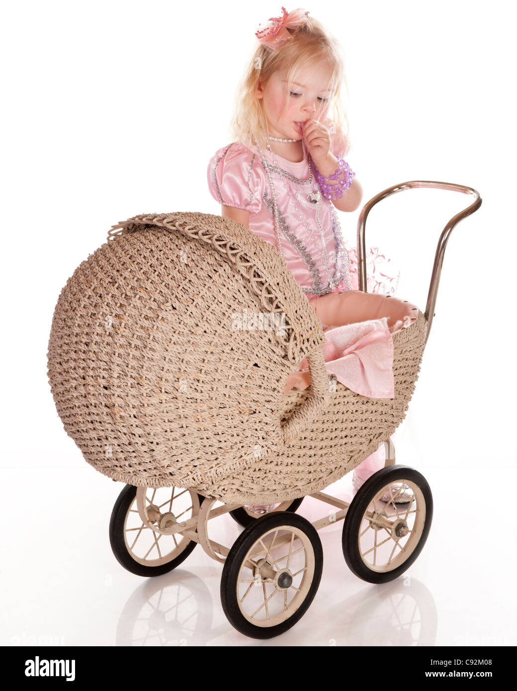 little girl dressed in pretty pink dress playing with old baby