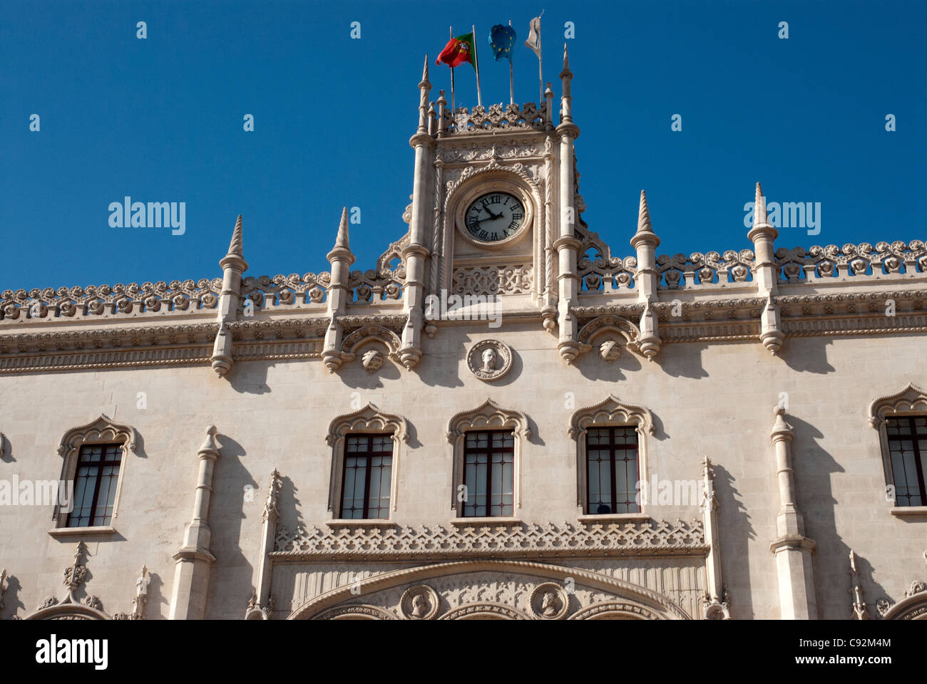 The facade of Rossio Station, in Estremadura, near Lisbon, is a fine baroque structure, with a  large clock, and flagpoles. Stock Photo