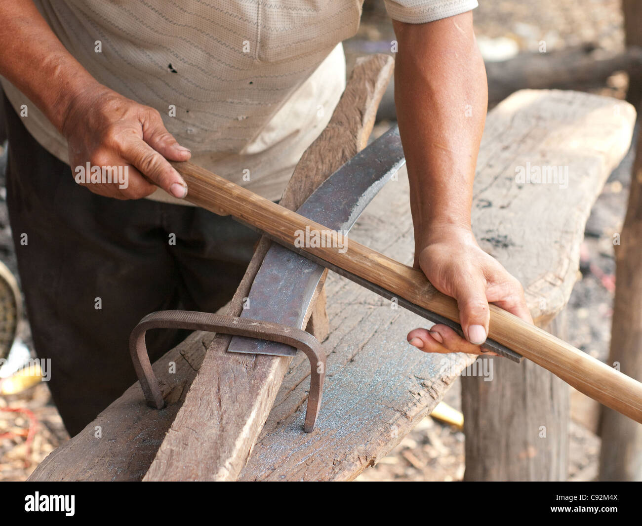 Blacksmith sharpening a sickle using a file mounted on a shaft Stock