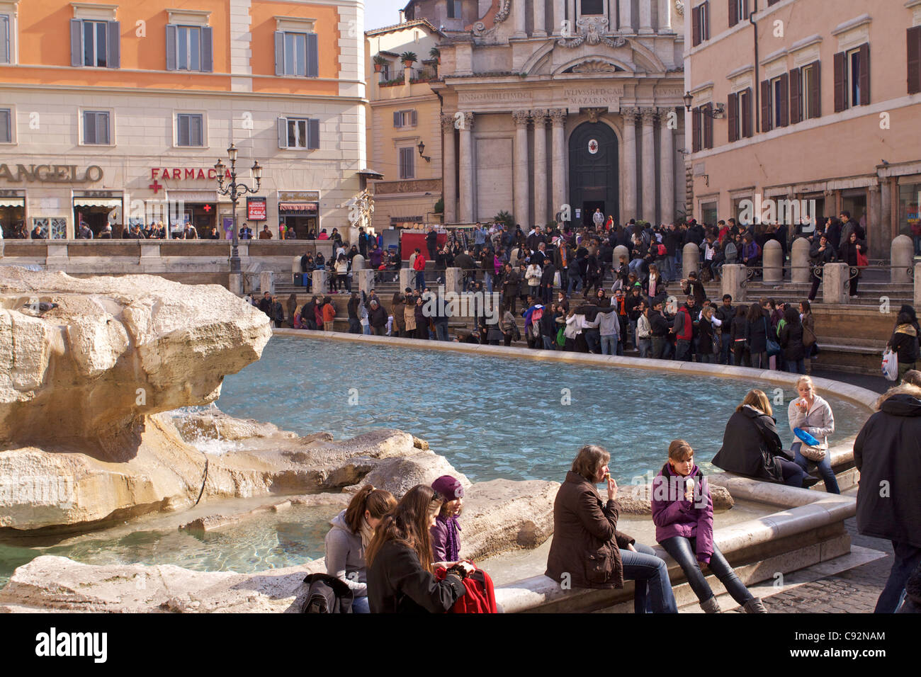 Crowds of tourists and visitors at the Trevi Fountain in front of the church of Santi Vincenzo e Anastasio in Rome. Stock Photo