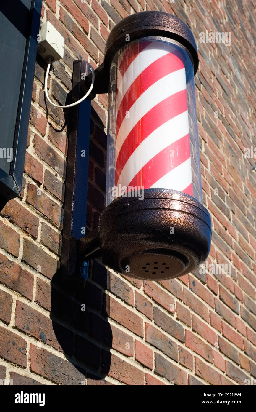 traditional striped barbers pole outside of a mens barber shop Stock Photo