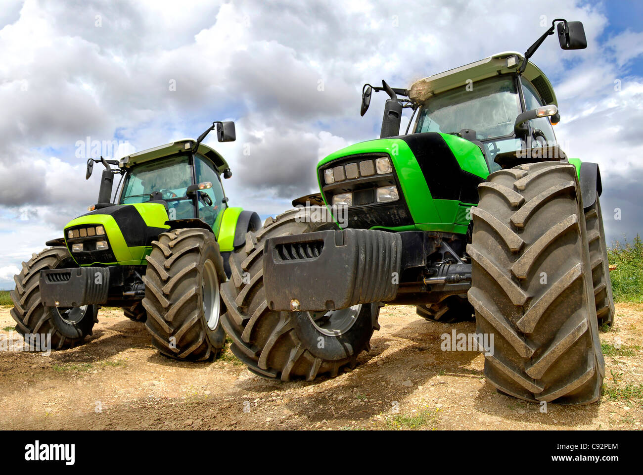 Green tractors in the field with a cloudy sky Stock Photo Alamy