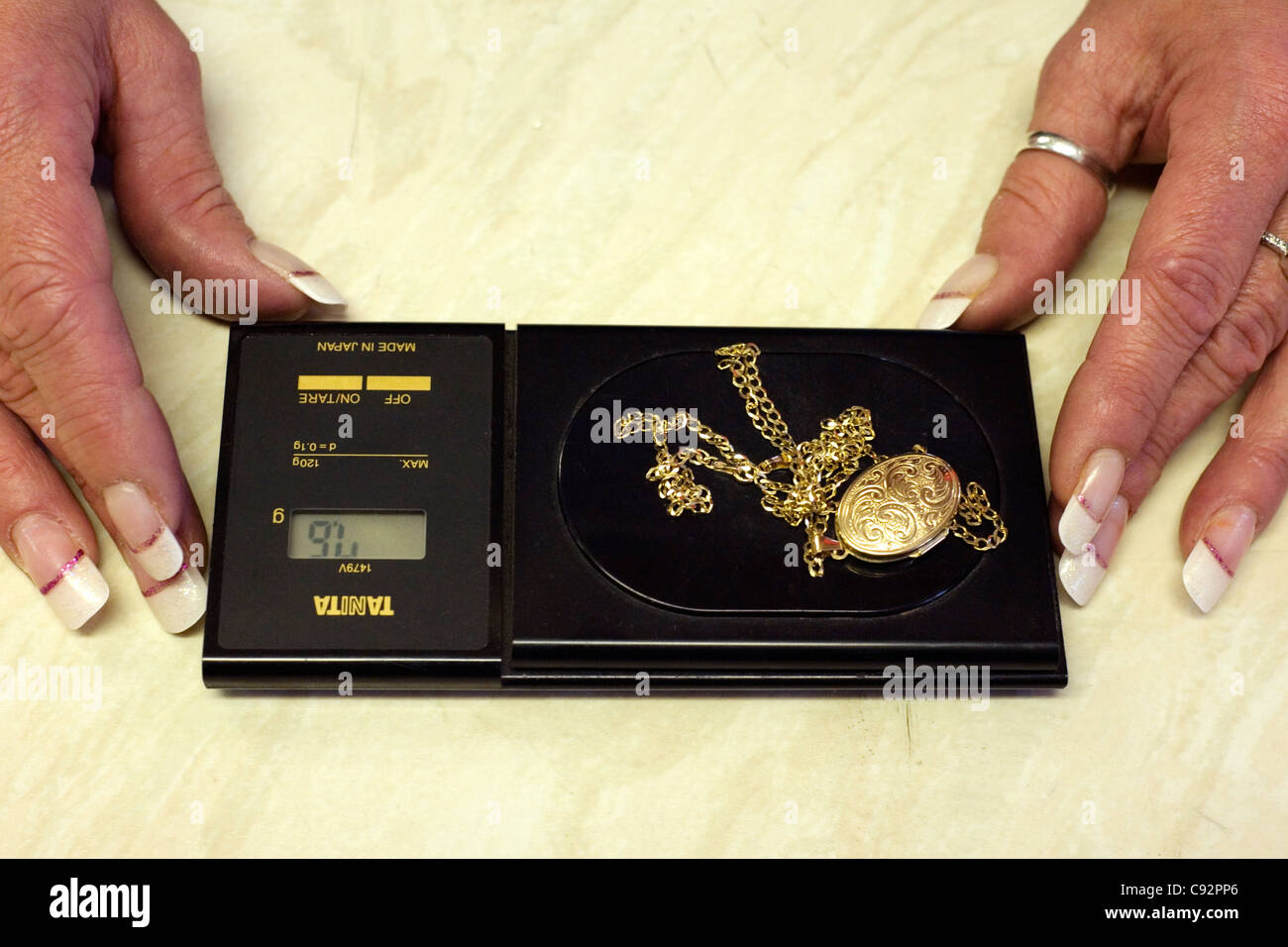 female jeweler weighing scrap gold on a set of electronic scales Stock Photo