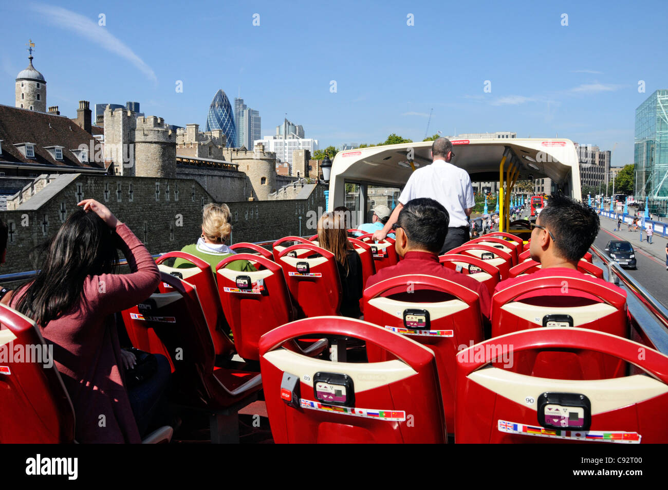 Tourists on double decker open top London sightseeing tour bus with views of Tower of London & City of London skyline on a blue sky summer day UK Stock Photo