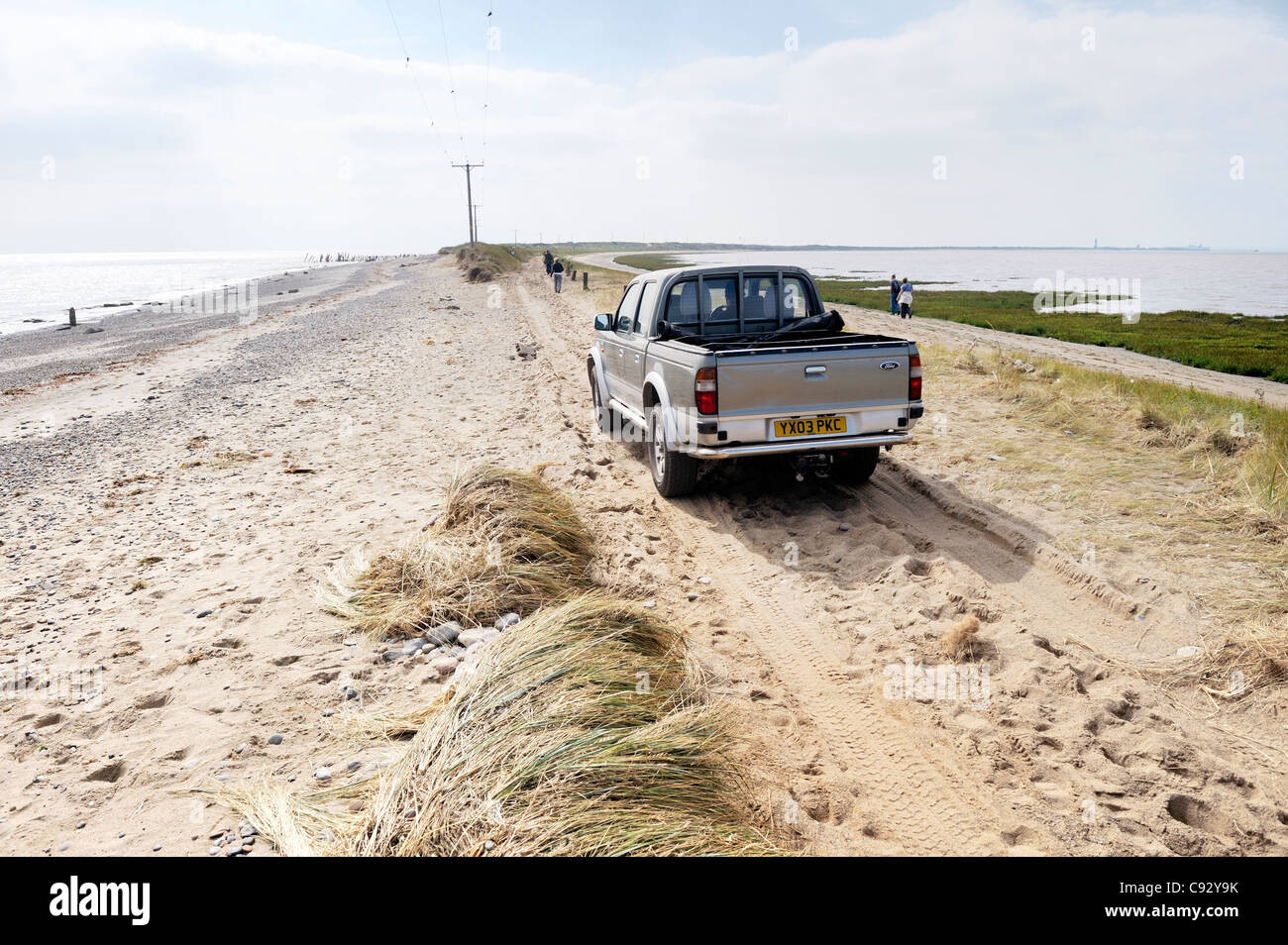 Sea storm coastal erosion at Spurn Head, Yorkshire east coast England. 4 wheel drive car on damaged narrowest point of sand spit Stock Photo