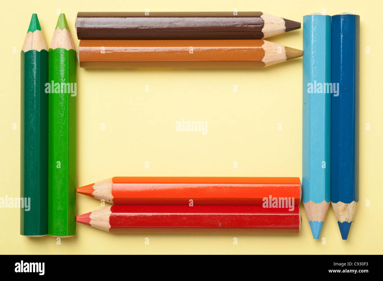 Colorful color pencils forming a rectangle frame on a piece of yellow paper Stock Photo
