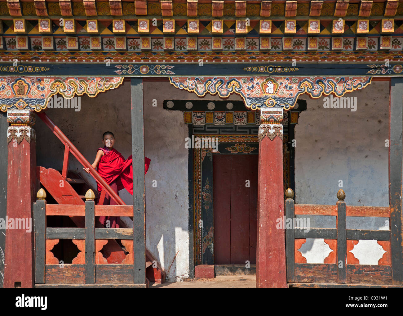 A young novice monk climbs down a staircase at the impressive Dzong, or fortress, at Trashigang. Stock Photo