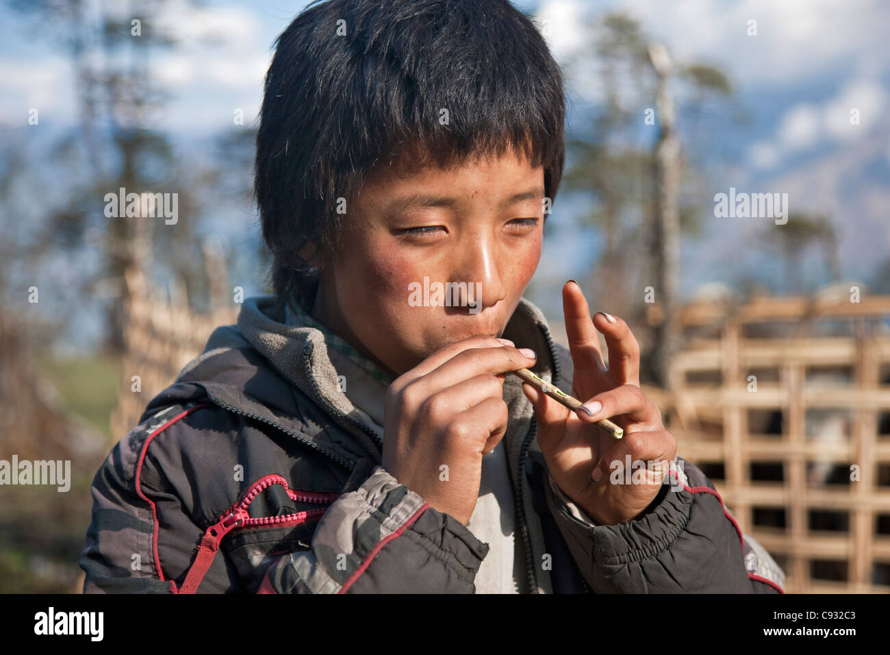 A young lad plays his homemade flute while on the Black Mountains pass known as Lawa La. Stock Photo