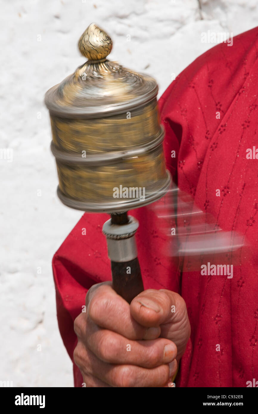 A Buddhist woman spins her hand-held prayer wheel in a clockwise direction. Stock Photo