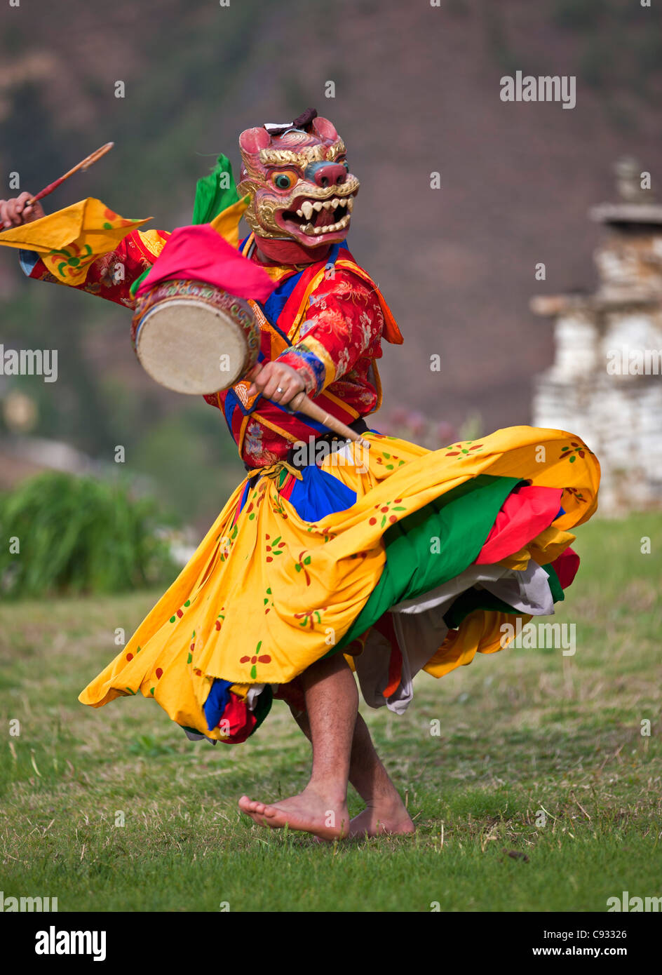 A masked dancer with a lag nga and bent drumstick performs Drametse Nga Cham. Stock Photo