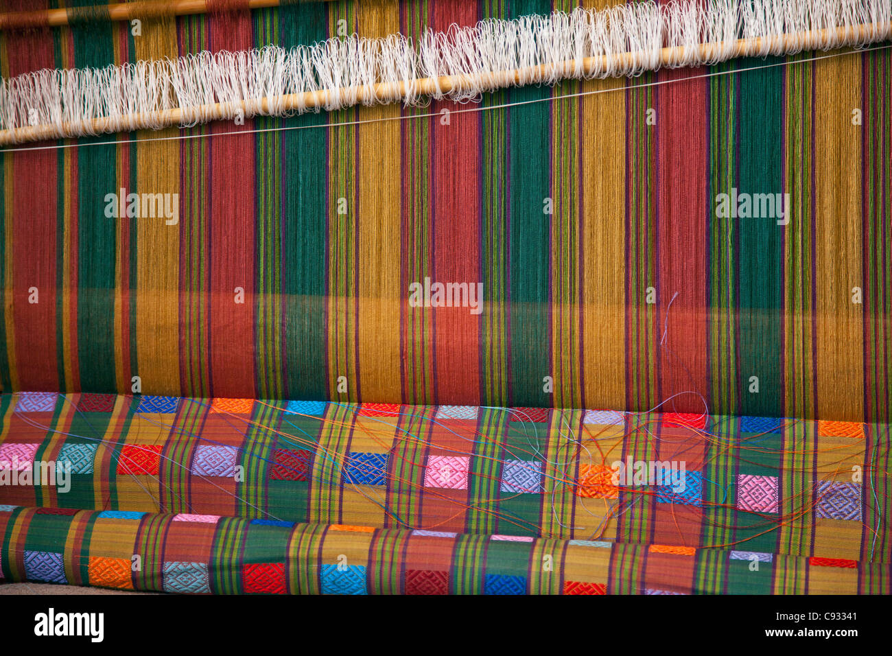 Beautifully patterned silk material being woven on a traditional wooden loom. Stock Photo