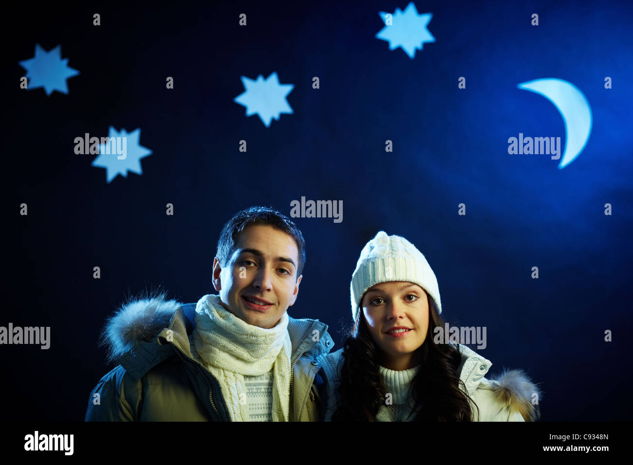 Portrait of happy couple looking at camera with moon and stars above their heads Stock Photo