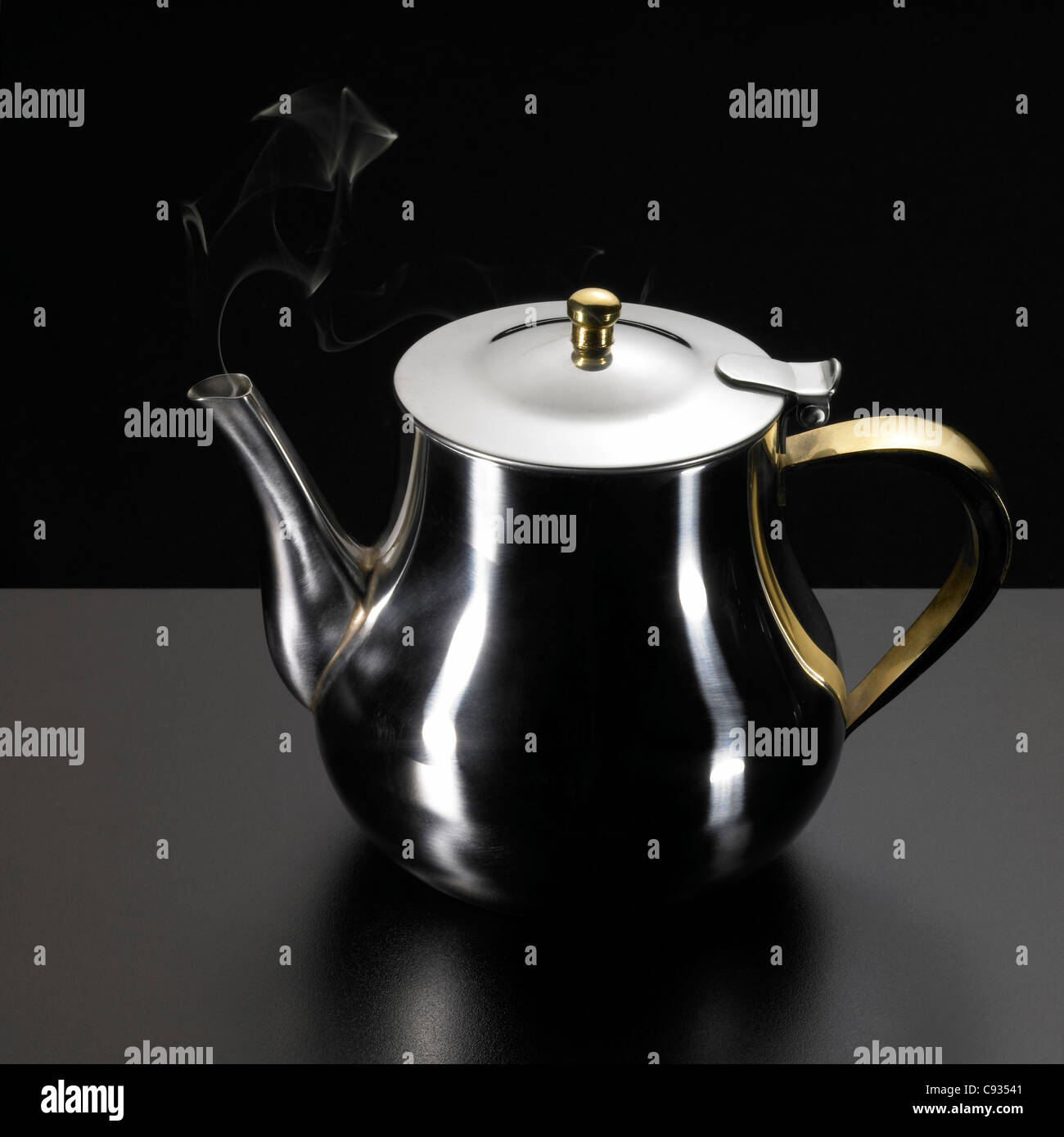 studio photography of a metallic tea pot and some damp in dark back ...