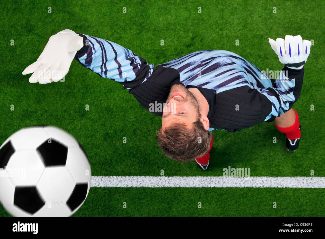 Overhead photo of a football goalkeeper missing saving the ball as it crosses over the line. Stock Photo
