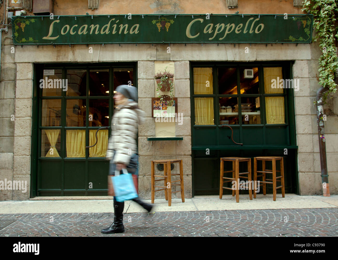 Italy, Veneto, Verona, Western Europe; A young woman walking in front of a typical restaurant Stock Photo