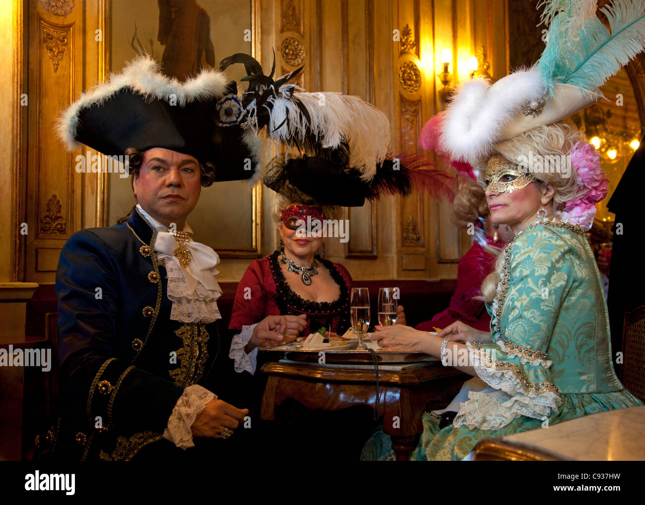 Venice, Veneto, Italy; Nostalgic reminiscence of the luxurious past with masked guests dressed for carnival. Stock Photo
