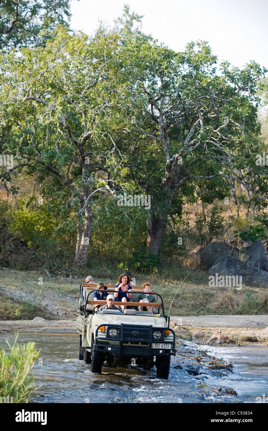 Malawi, Majete Wildlife Reserve.  Family on safari cross the Mkulumadzi River in their safari vehicle. Stock Photo
