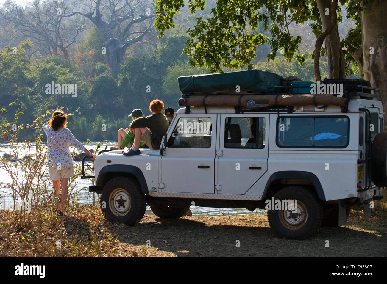 Malawi, Majete Wildlife Reserve.  Family on safari look out across the Shire River from their safari vehicle. MR Stock Photo