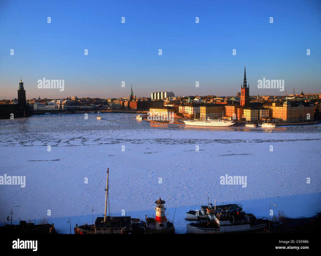 Church steeple on Riddarholmen Island above frozen waters of the Riddarfjarden in Stockholm in low winter light Stock Photo