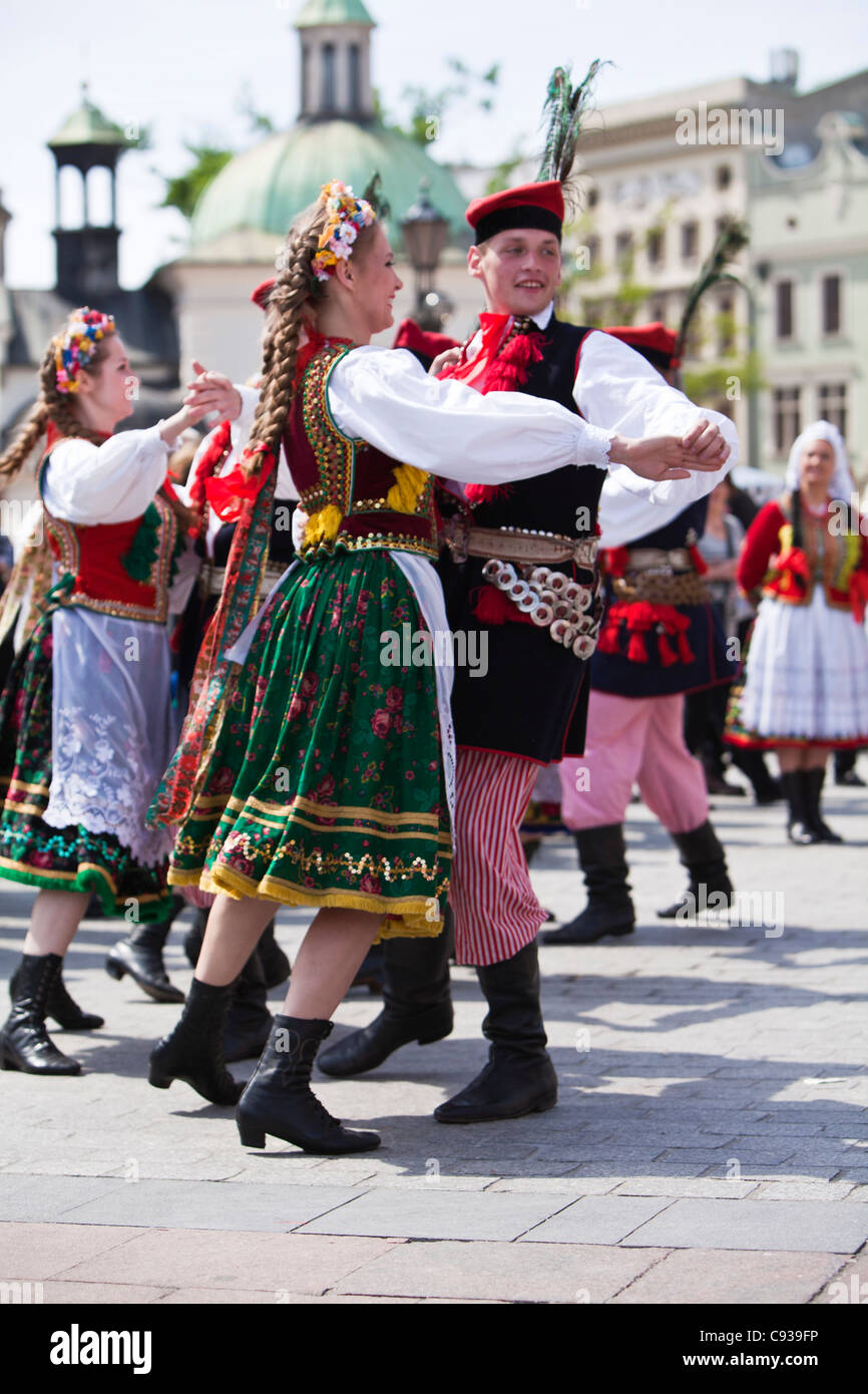 Poland, Cracow. Polish girls and boys in traditional dress dancing in Market Square. Stock Photo