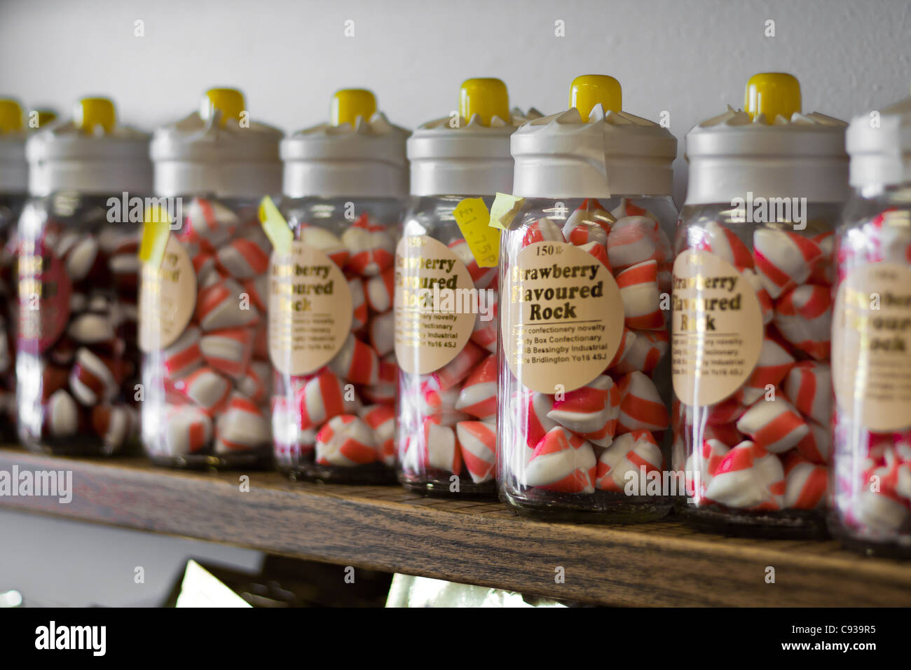 Strawberry flavoured holiday stick of rock in jars and bags of sweets for sale, the perfect holiday beach gift and present. Stock Photo