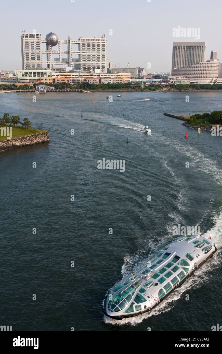 A sight-seeing boat heads out into Tokyo Bay with the distinctive Fuji television building behind. Odaiba, Tokyo, Japan Stock Photo