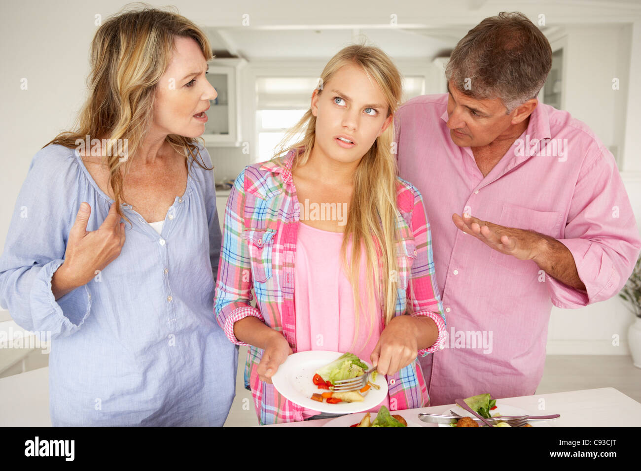 Parents making teenage daughter do chores at home Stock Photo