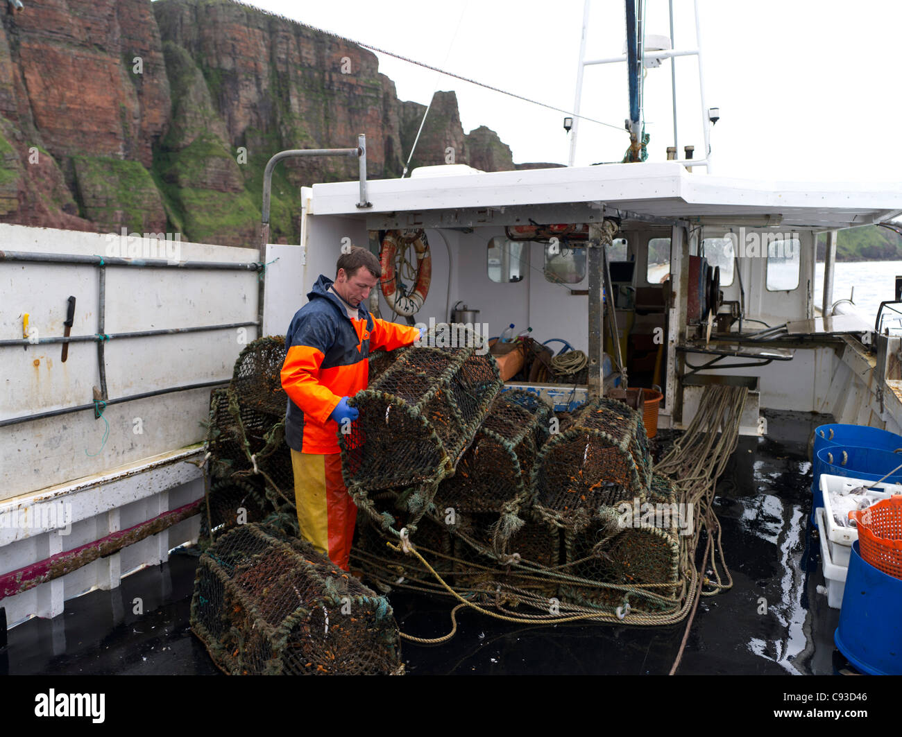 dh  FISHING ORKNEY Fishermen stacking creels aboard fishing boat to lay the pots fisherman lobster pot Stock Photo