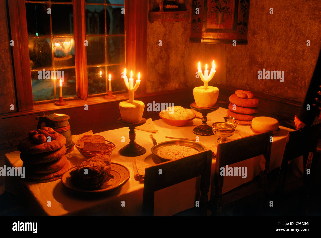 Old Swedish Christmas table or julbord from 1850s at Skansen in Stockholm with cheese, baked bread, roast ham, and candles Stock Photo