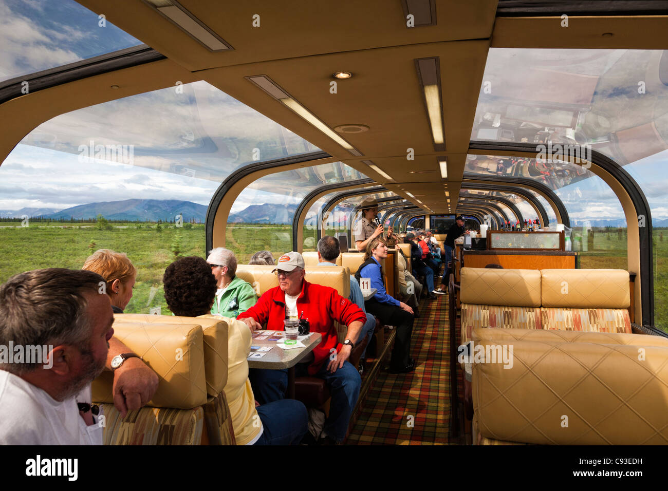 Tourists on train to Denali National Park in Alaska enjoy refreshments and narration from Park Ranger. Stock Photo