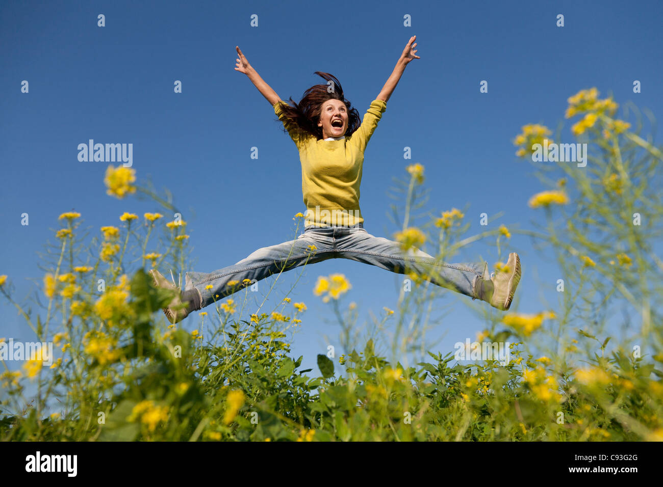 Happy and beautiful young girl jumping high in a summer field Stock Photo