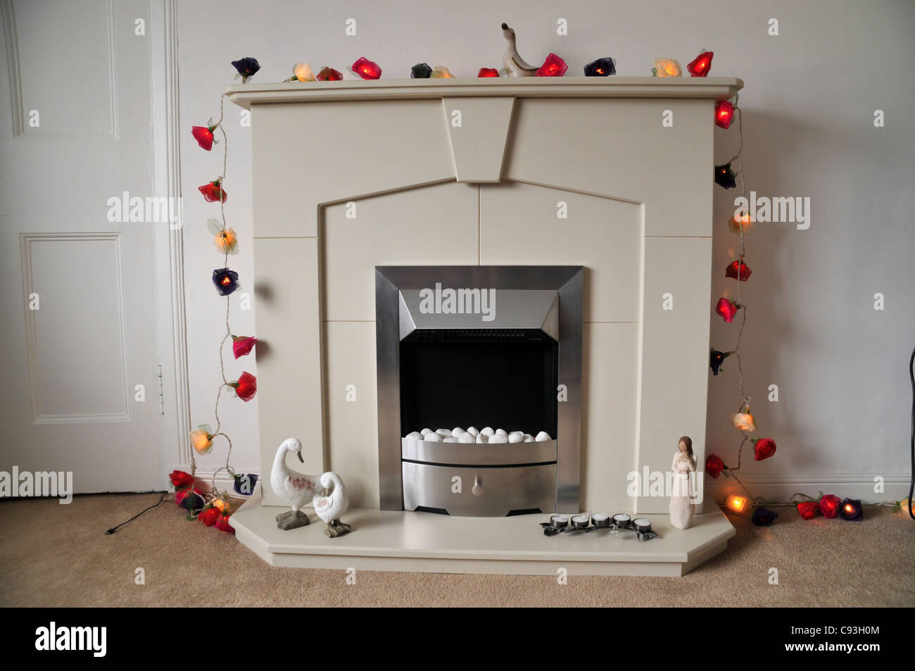 a modern white electric fireplace decorated with fairy lights. Stock Photo