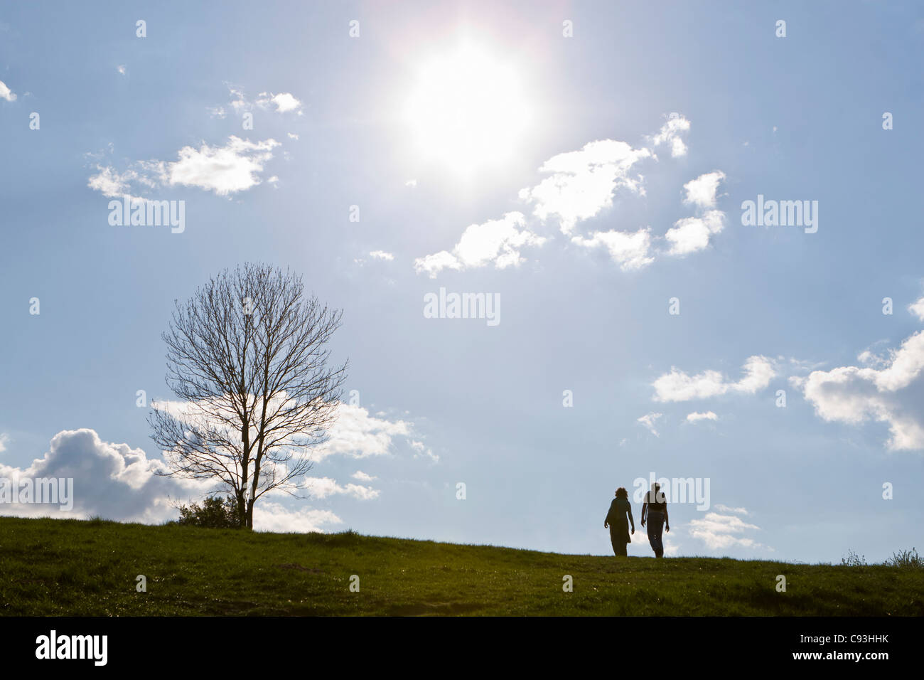 Two young people climb a grassy hill Stock Photo
