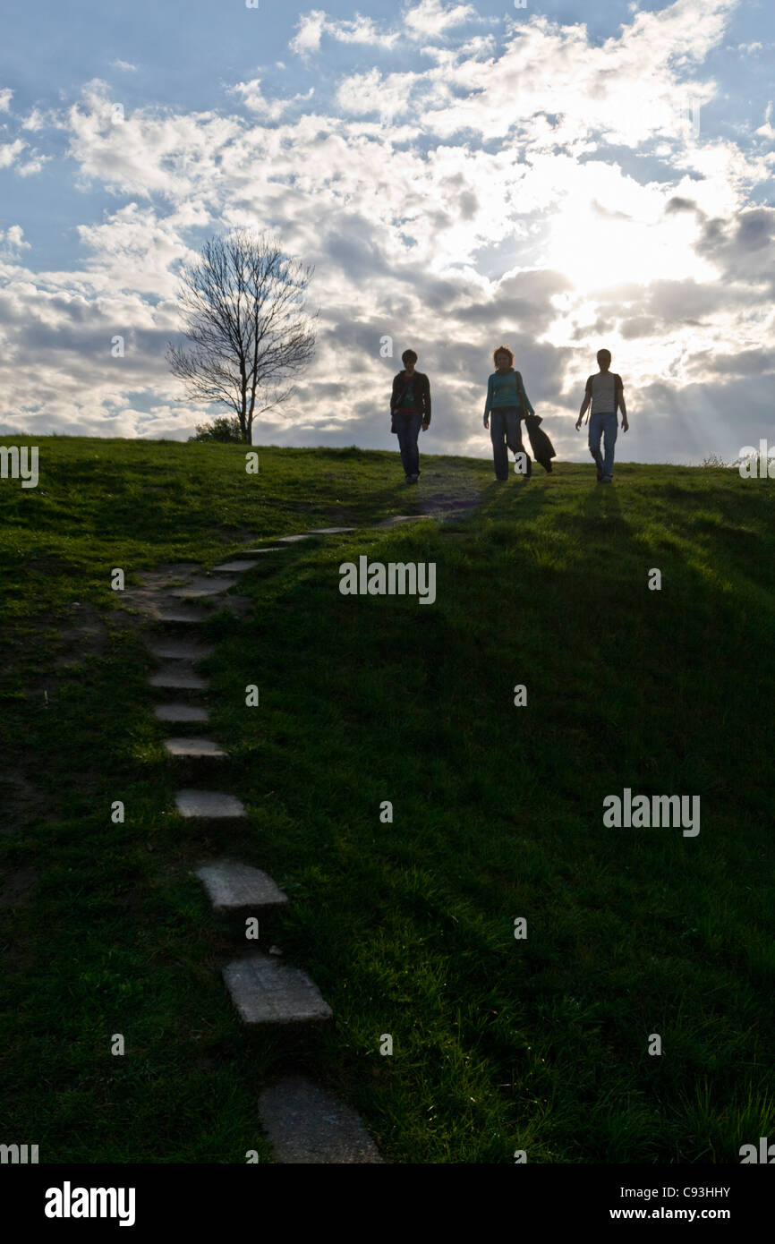 Three young people walk down a grassy hill Stock Photo
