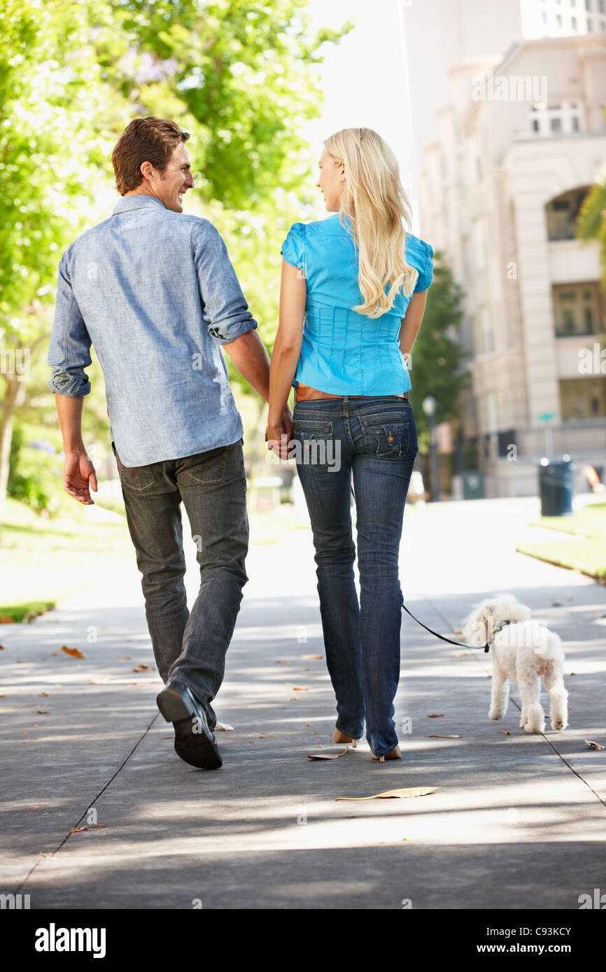 Couple walking with dog in city street Stock Photo - Alamy