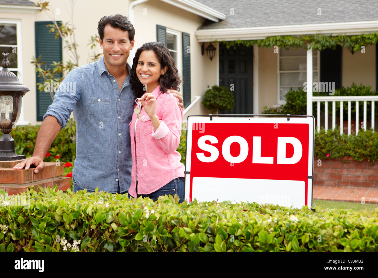 Hispanic couple outside home with sold sign Stock Photo - Alamy