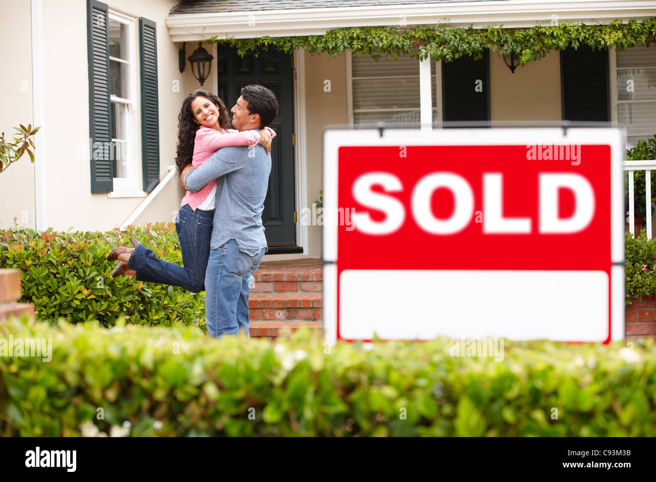 Hispanic couple outside home with sold sign Stock Photo - Alamy
