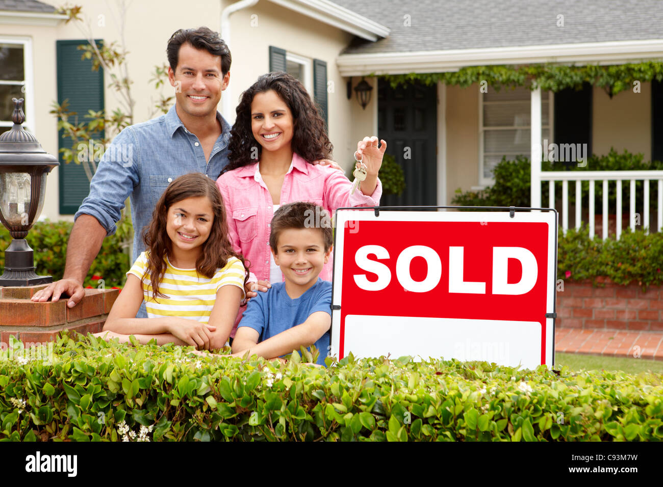 Hispanic family outside home with sold sign Stock Photo - Alamy
