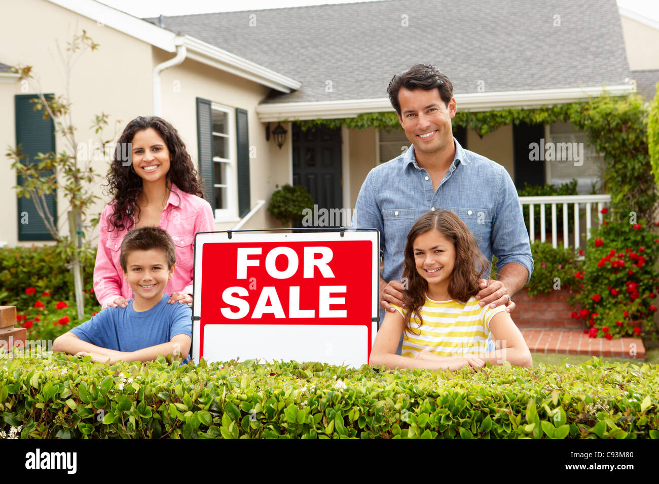 Hispanic family outside home with for sale sign Stock Photo - Alamy