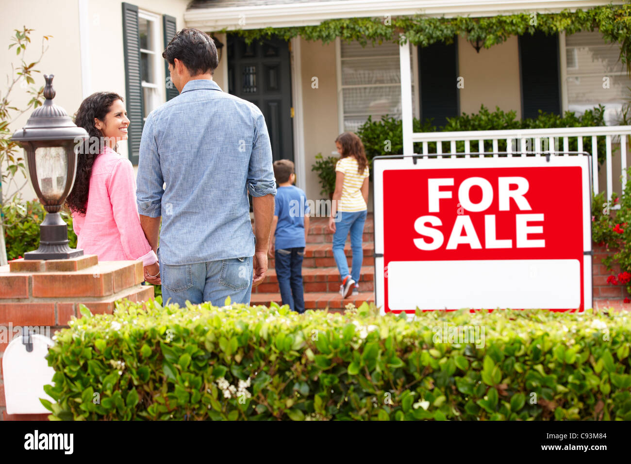 Hispanic family outside home with for sale sign Stock Photo - Alamy