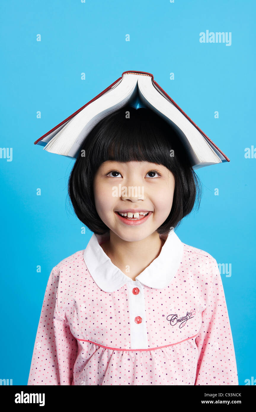 Young girl with book on head , balancing, studio shot Stock Photo - Alamy