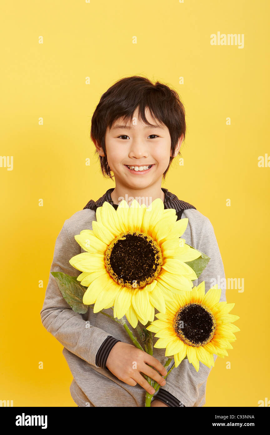 Young boy holding sunflower, smiling Stock Photo Alamy