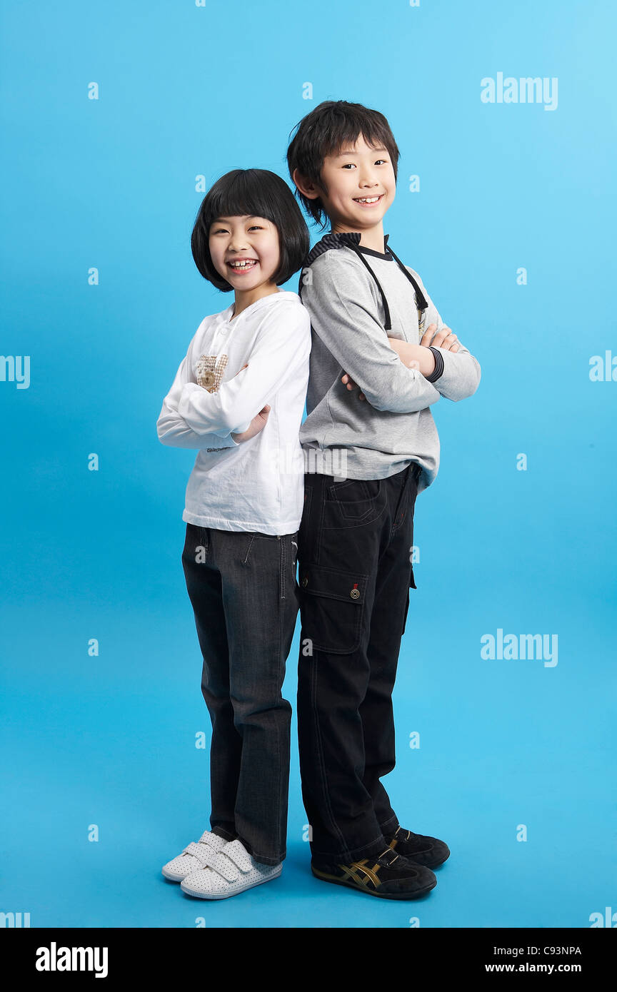 Boy and girl standing back to back, studio shot Stock Photo - Alamy