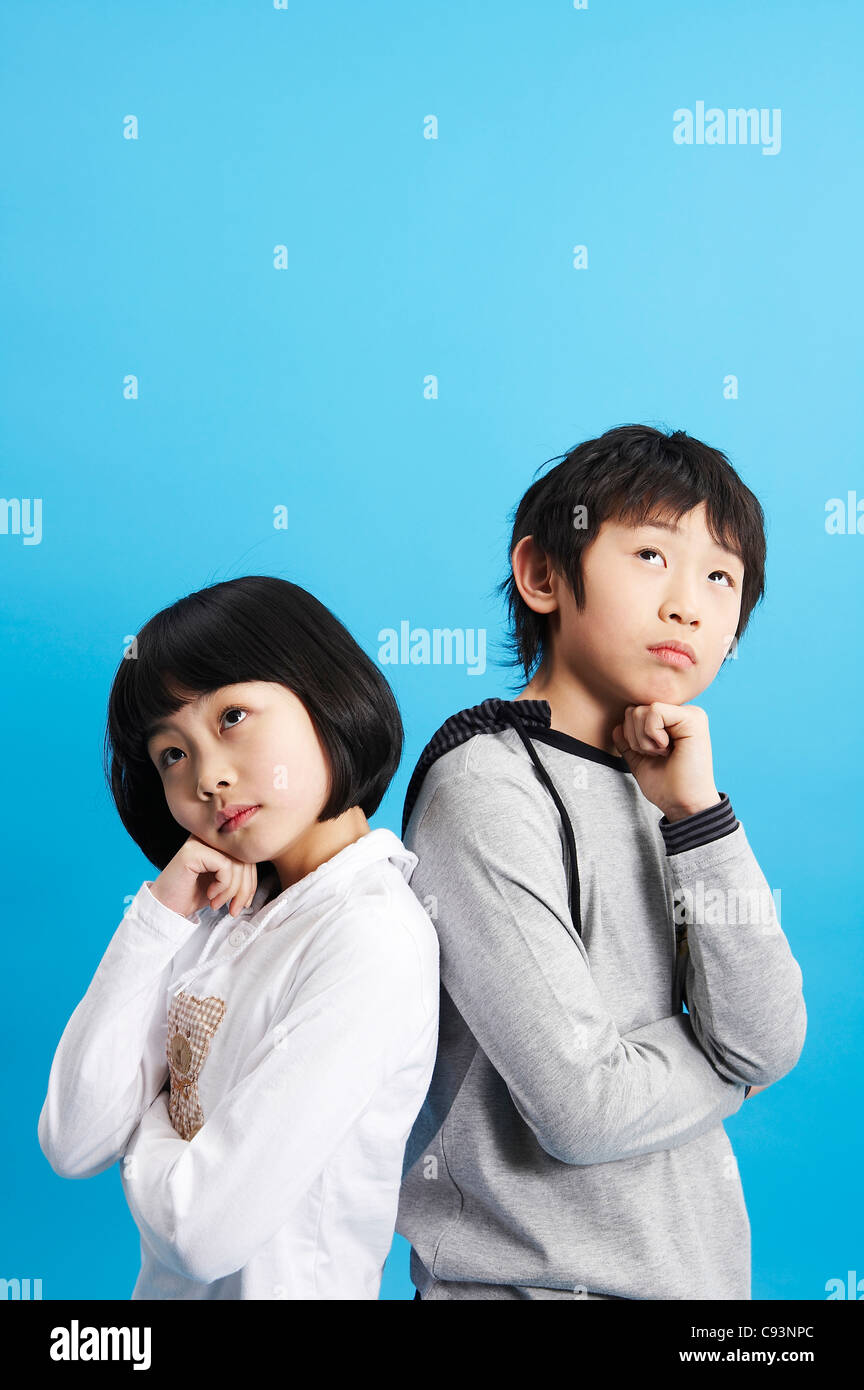 Boy and girl standing back to back, studio shot Stock Photo - Alamy