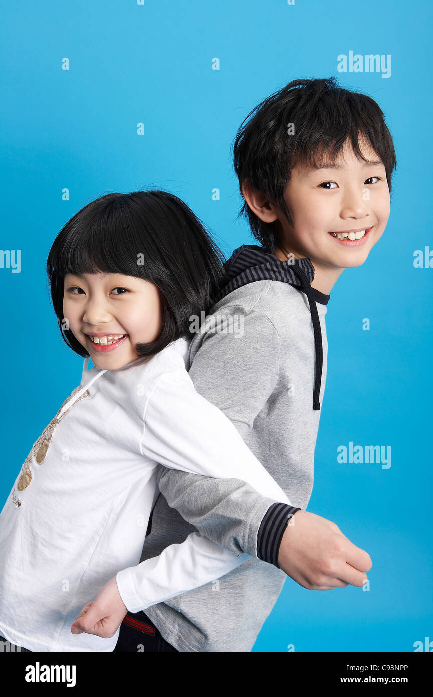 Boy and girl standing back to back, studio shot Stock Photo - Alamy